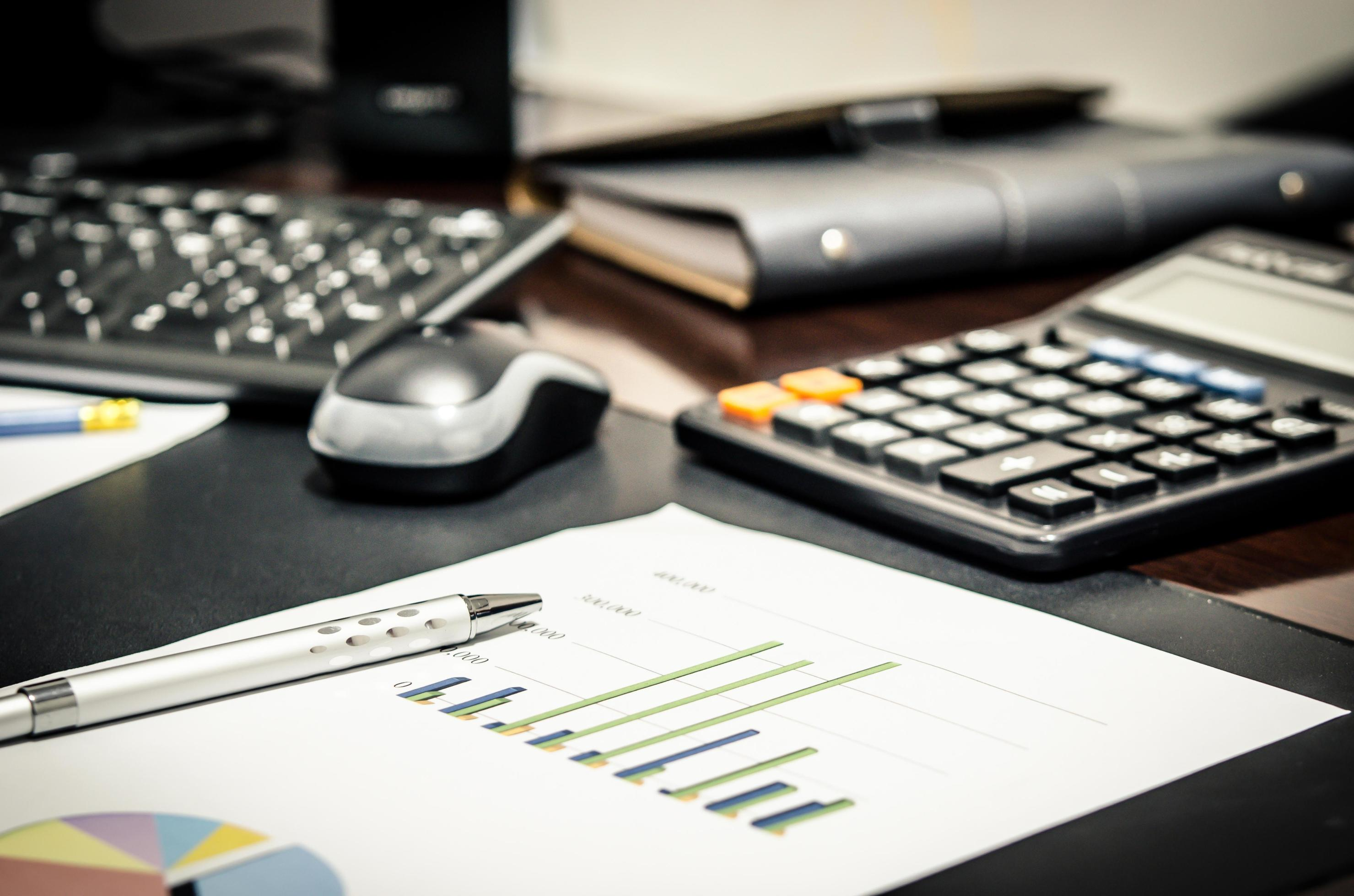 Mesa de trabalho com relatórios, gráficos e calculadora