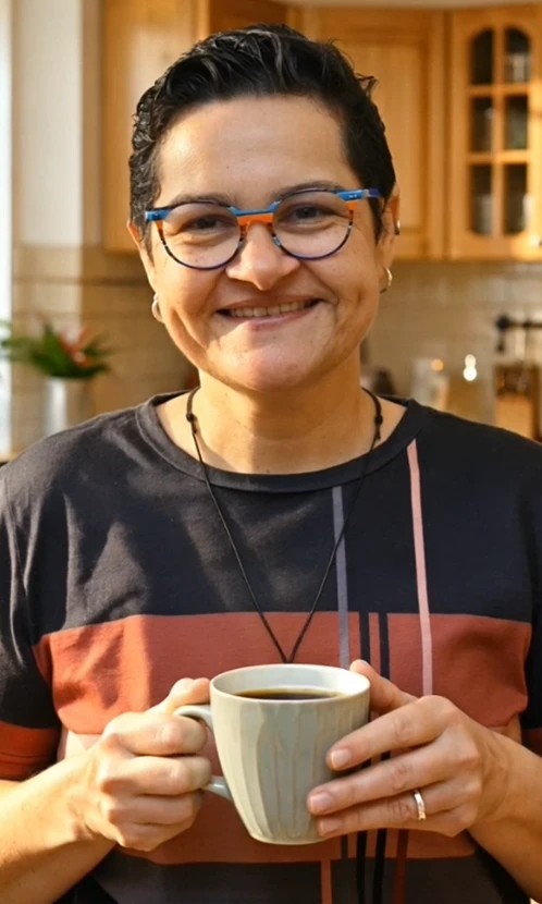 Jeane Marilá smiling with a cup of coffee in her hand